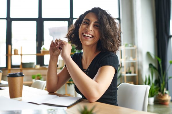 happiness and inspiration, overjoyed multiracial coach sitting with pen and looking at camera happiness and inspiration, overjoyed multiracial coach sitting with pen and looking at camera