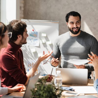 Professionals in diverse group collaborate in boardroom engaging in lively brainstorming session